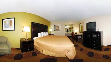 A hotel room with a large bed, a desk with a computer, a television, and a microwave.