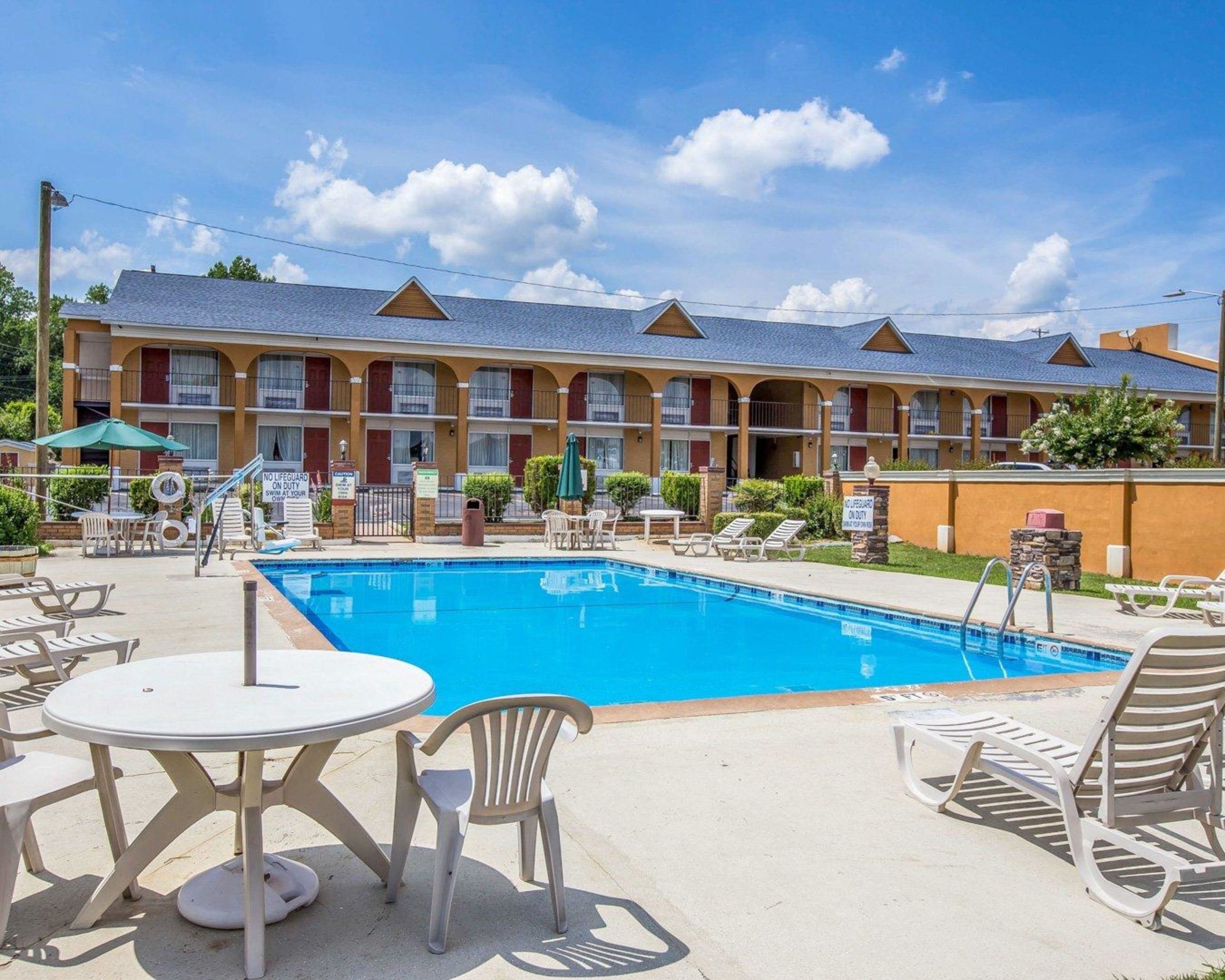 Un hotel con piscina, mobiliario exterior y señal de socorrista de servicio.