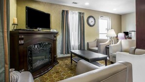 A hotel room with a fireplace, a television, a clock, and a desk with a lamp. - Quality Inn Greenwood Hwy 25 (Greenwood)