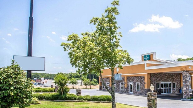 A Quality Inn hotel with a prominent sign, stone facade, and a parking lot. - Quality Inn Greenwood Hwy 25 (Greenwood)