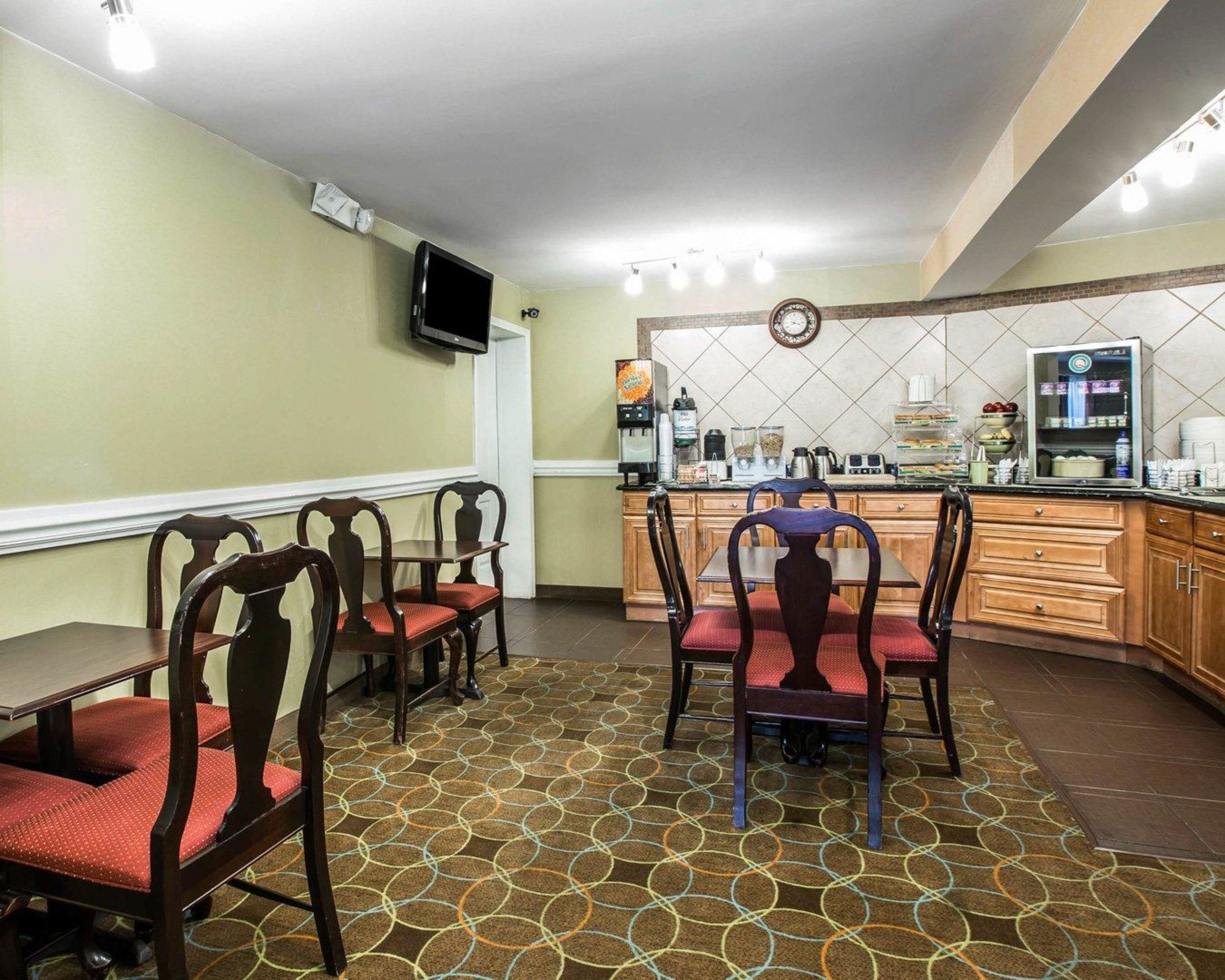 A dining area with a table and chairs, a coffee station, and a kitchen area with a tiled backsplash.