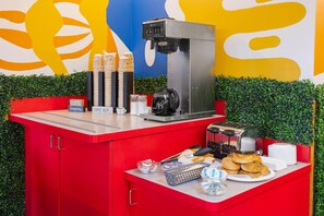 A coffee station with a coffee machine, cups, and pastries. - Days Inn By Wyndham Pigeon Forge South (Pigeon Forge)