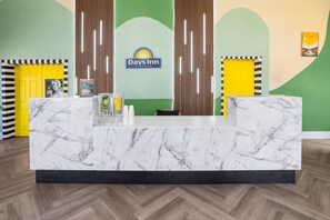 A reception desk with a marble top, a Days Inn sign, and a yellow door.
