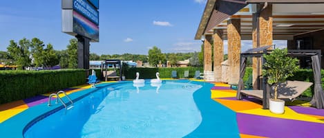 Una piscina con adornos de cisnes, una zona de estar cubierta y un letrero del Smoky Mountain Convention Center.