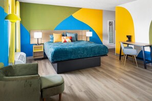 Una habitació d'hotel amb un llit, taules de nit, un escriptori i una cadira.