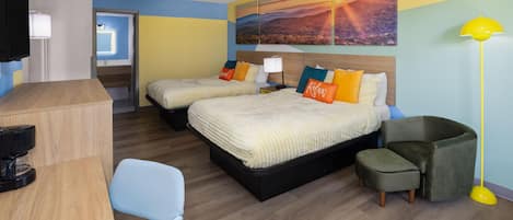 Une chambre d’hôtel avec deux lits, un bureau, une chaise, un canapé, une lampe et un tableau au mur.