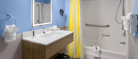 A bathroom with a shower, a sink, a mirror, and a towel rack.