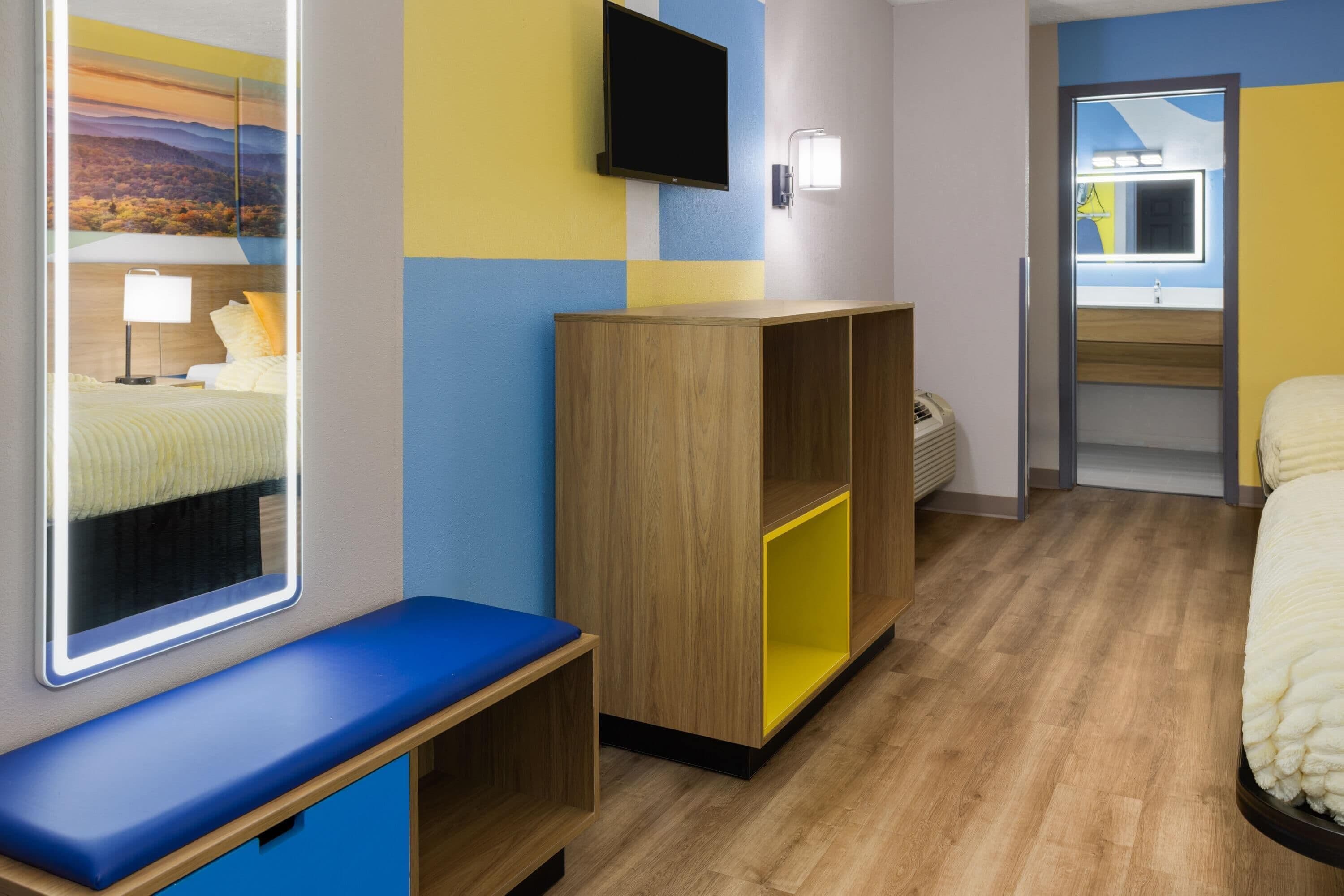 A hotel room with a bed, a desk, a wardrobe, and a television.