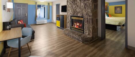 Una sala de estar moderna con chimenea, un comedor con mesa y sillas, y un dormitorio con cama.