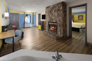A modern living room with a fireplace, a dining area with a table and chairs, and a bedroom with a bed.