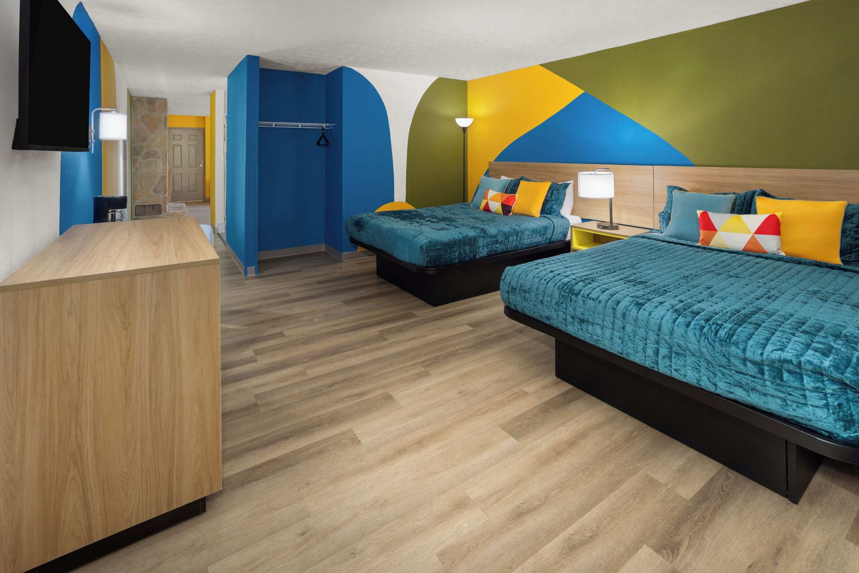 A hotel room with two beds, a desk, a TV, and a bathroom.