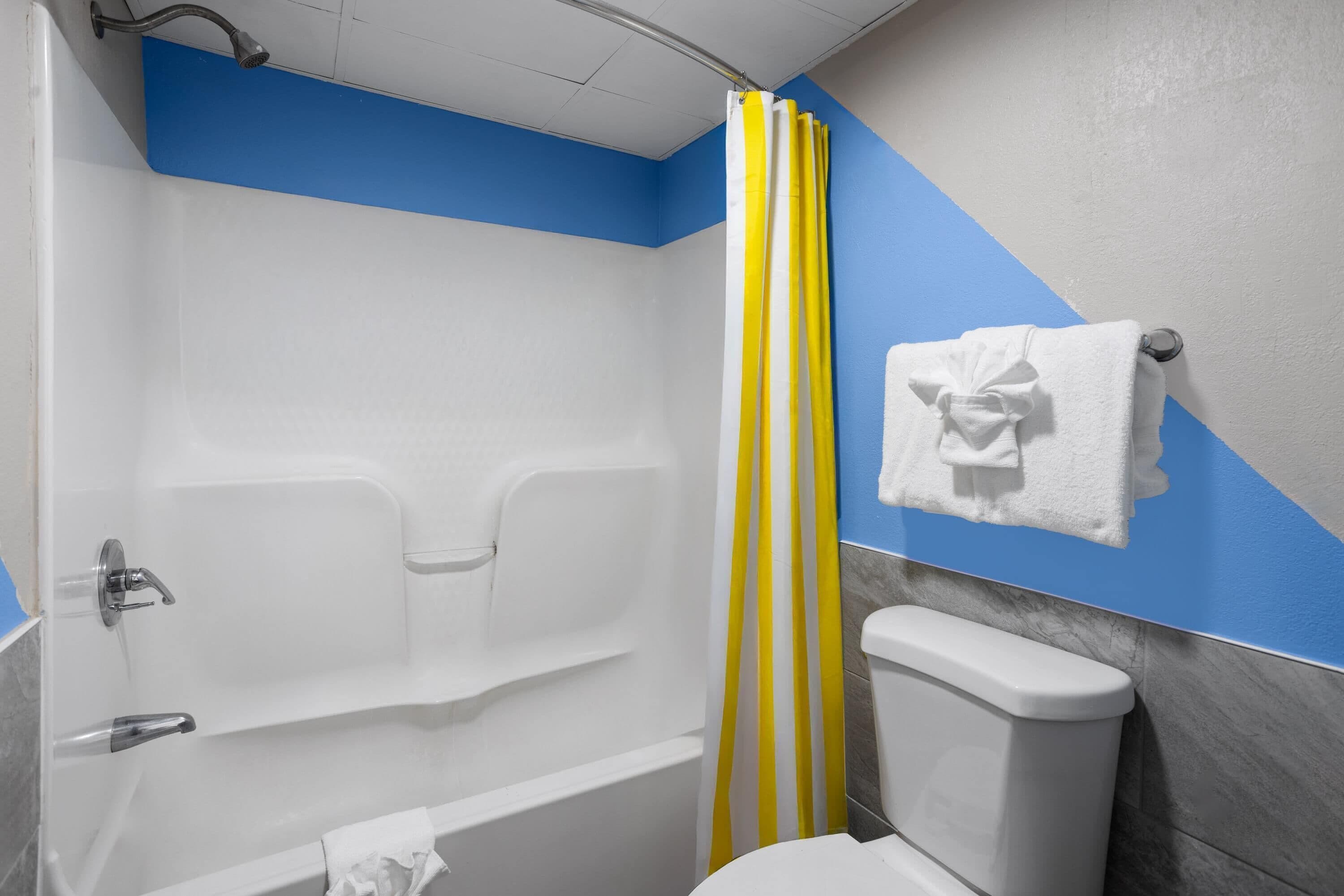 Un baño con ducha, inodoro y toallero.