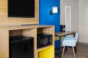Una kitchenette compacta con microondas, cafetera y refrigerador pequeño.