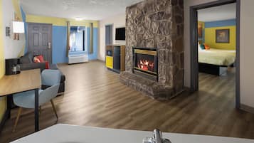 Una sala de estar moderna con chimenea, un comedor y un dormitorio visibles a través de una puerta abierta.