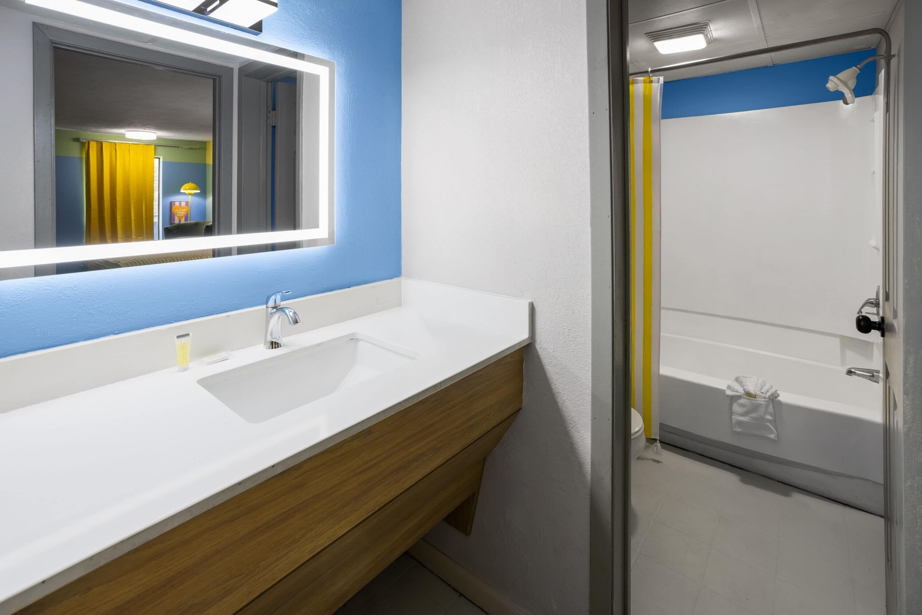 Un baño con un lavamanos blanco, un espejo y una zona de ducha.