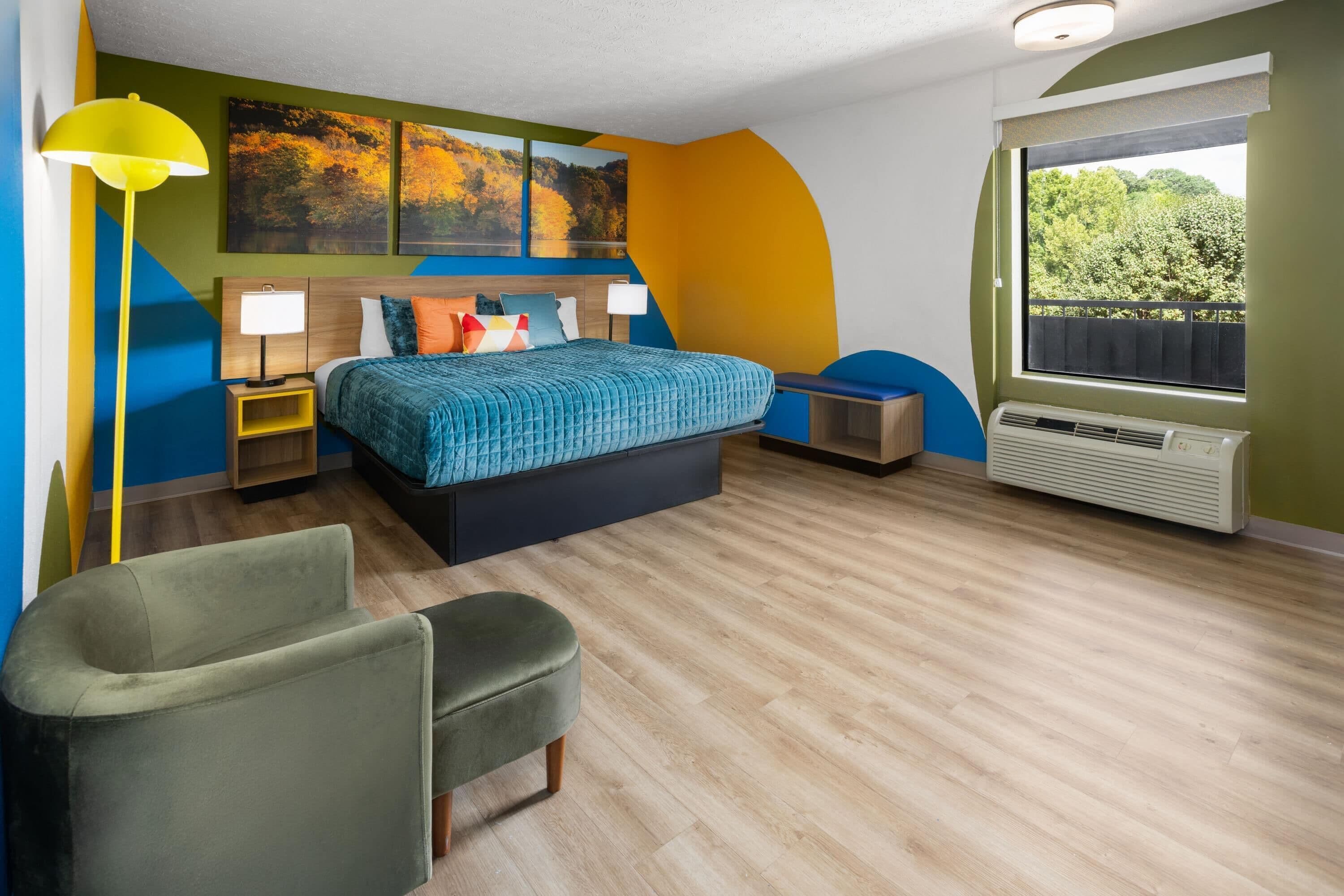 Un dormitorio moderno con cama, mesitas de noche, una silla, una ventana con vistas y un radiador.