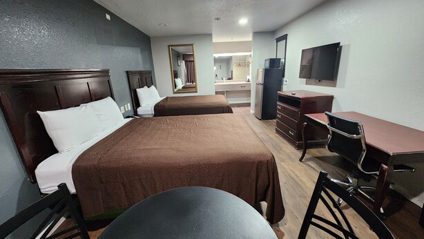 A hotel room with two single beds, a desk with a chair, a dresser, a television, and a mirror. - Express Inn Hobby (Houston)