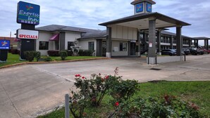 A hotel with a sign for Express Inn Hobby, a fountain, and a parking area. - Express Inn Hobby (Houston)