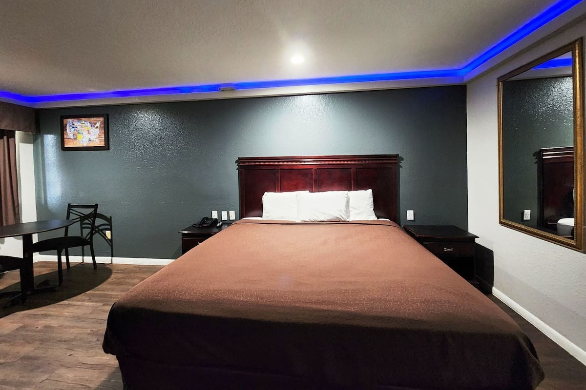 A hotel room with a bed, bedside tables, a desk, and a chair.