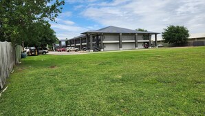 A two-story building with a covered patio area and a fenced yard. - Express Inn Hobby (Houston)