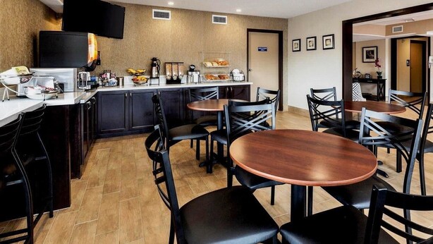 Un área de comedor moderna de hotel con una barra de cocina, mesas y sillas.