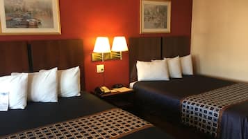 A hotel room with two beds, a nightstand with a phone, and wall-mounted lamps.