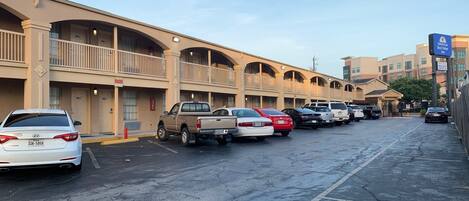 A parking lot with several cars parked in front of a motel with multiple balconies and a sign for "Americas Best Value Inn".