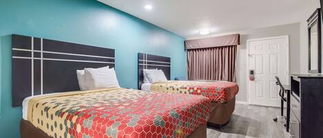 A hotel room with two beds, teal walls, and a wooden floor.