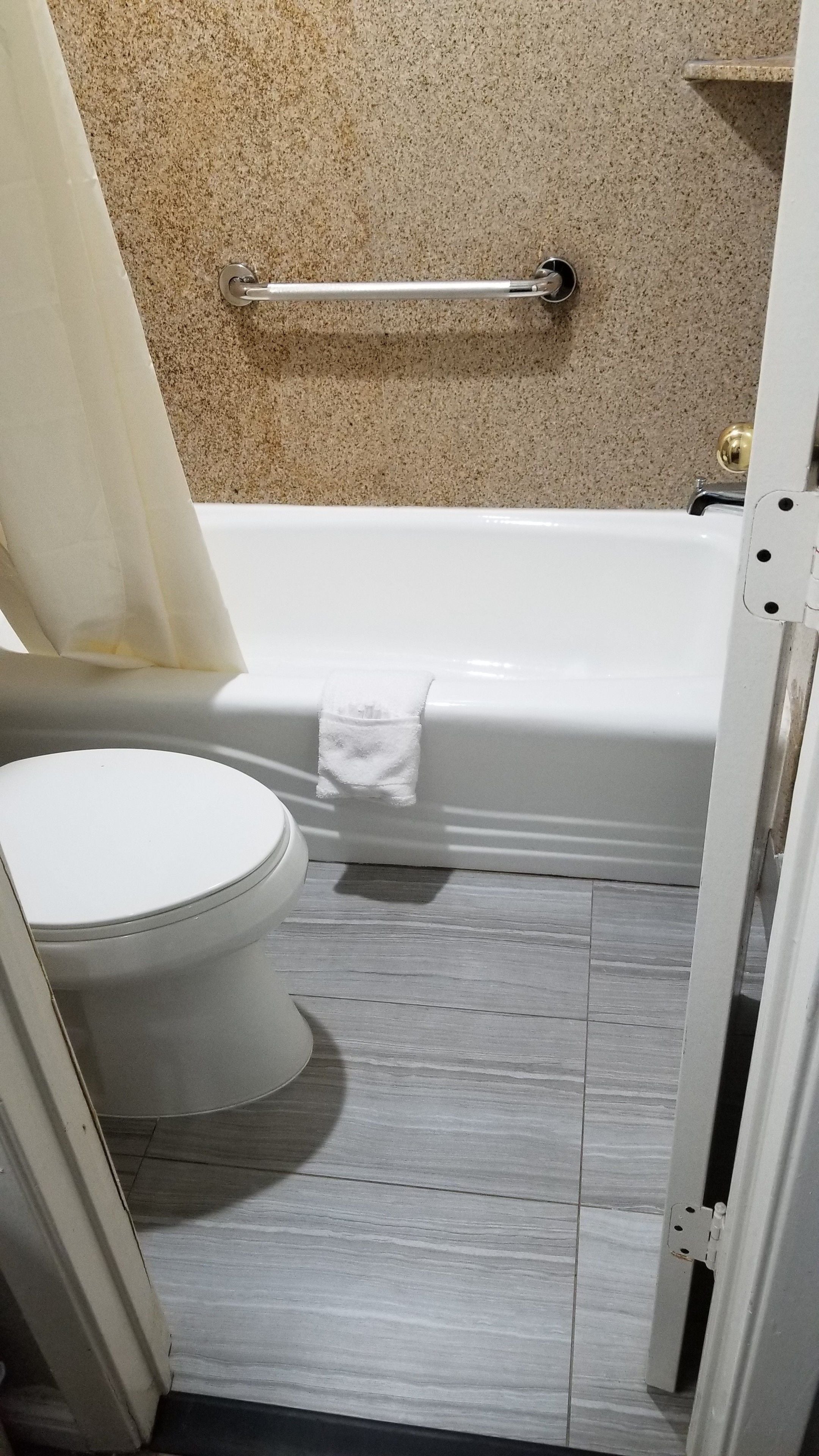 Un baño con inodoro blanco, bañera y cortina de ducha.