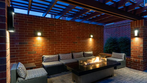 Une terrasse extérieure avec un mur en briques, un foyer et des sièges d’extérieur.