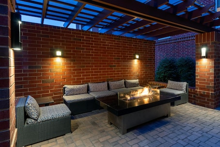 An outdoor patio with a brick wall, a fire pit, and outdoor seating.