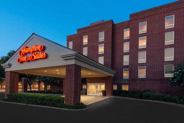 A Hampton Inn & Suites building with a brick facade and a neon sign.