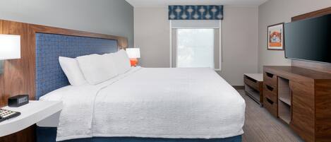 A hotel room with a bed, bedside table, TV, and a window with a view.