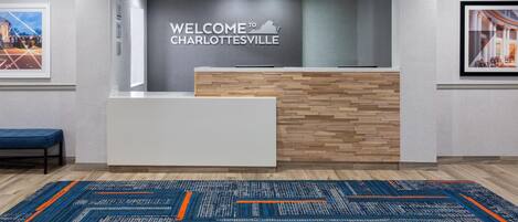 A reception area with a 'Welcome to Charlottesville' sign, a reception desk, and a patterned carpet.