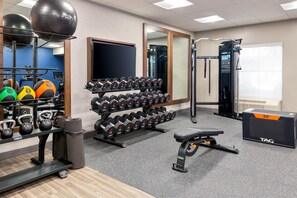 A gym with exercise equipment, including dumbbells, kettlebells, and a bench. - Hampton Inn & Suites Charlottesville-At the University (Charlottesville)