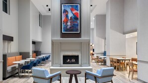 Un espace de détente moderne, doté d’une cheminée, de différents coins salon et d’un grand tableau accroché au mur.