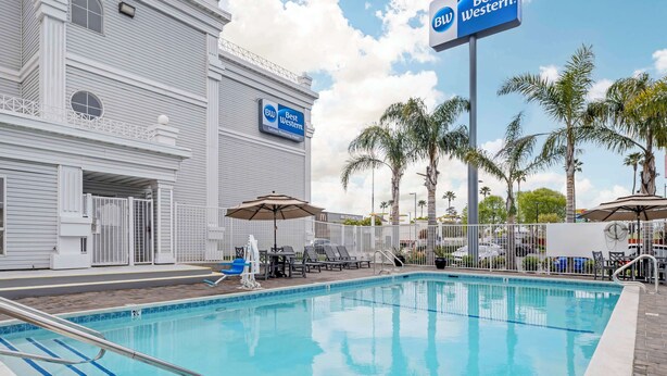 Un espace piscine équipé de chaises longues, de parasols et d’un panneau Best Western.