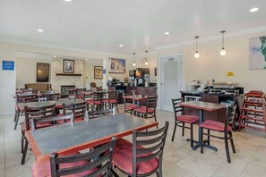 Guests can enjoy meals and socialize in this dining area, which features tables, chairs, a coffee station, and a fireplace.