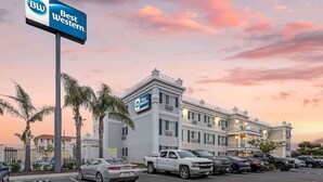 Un hôtel Best Western doté d’un parking, de palmiers et offrant une vue sur un ciel au coucher du soleil.