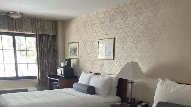 A hotel room with two beds, a desk, a lamp, and a window with curtains. - SureStay Plus by Best Western Woodbury Inn (Woodbury)