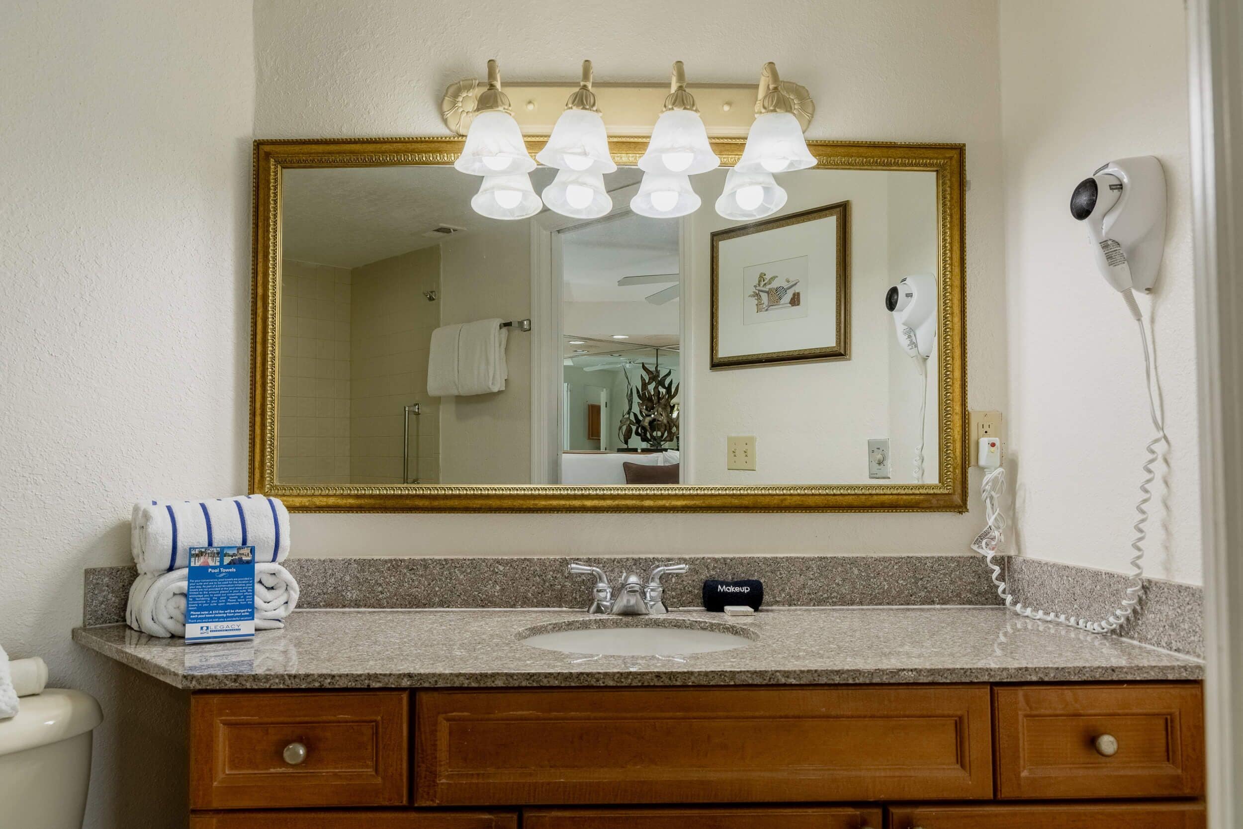 A bathroom with a large mirror, a sink, a hairdryer, and a towel rack.