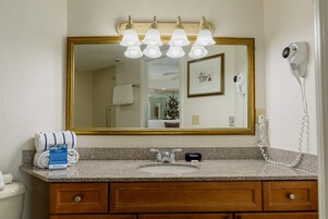 A bathroom with a large mirror, a sink, a hairdryer, and a towel rack.