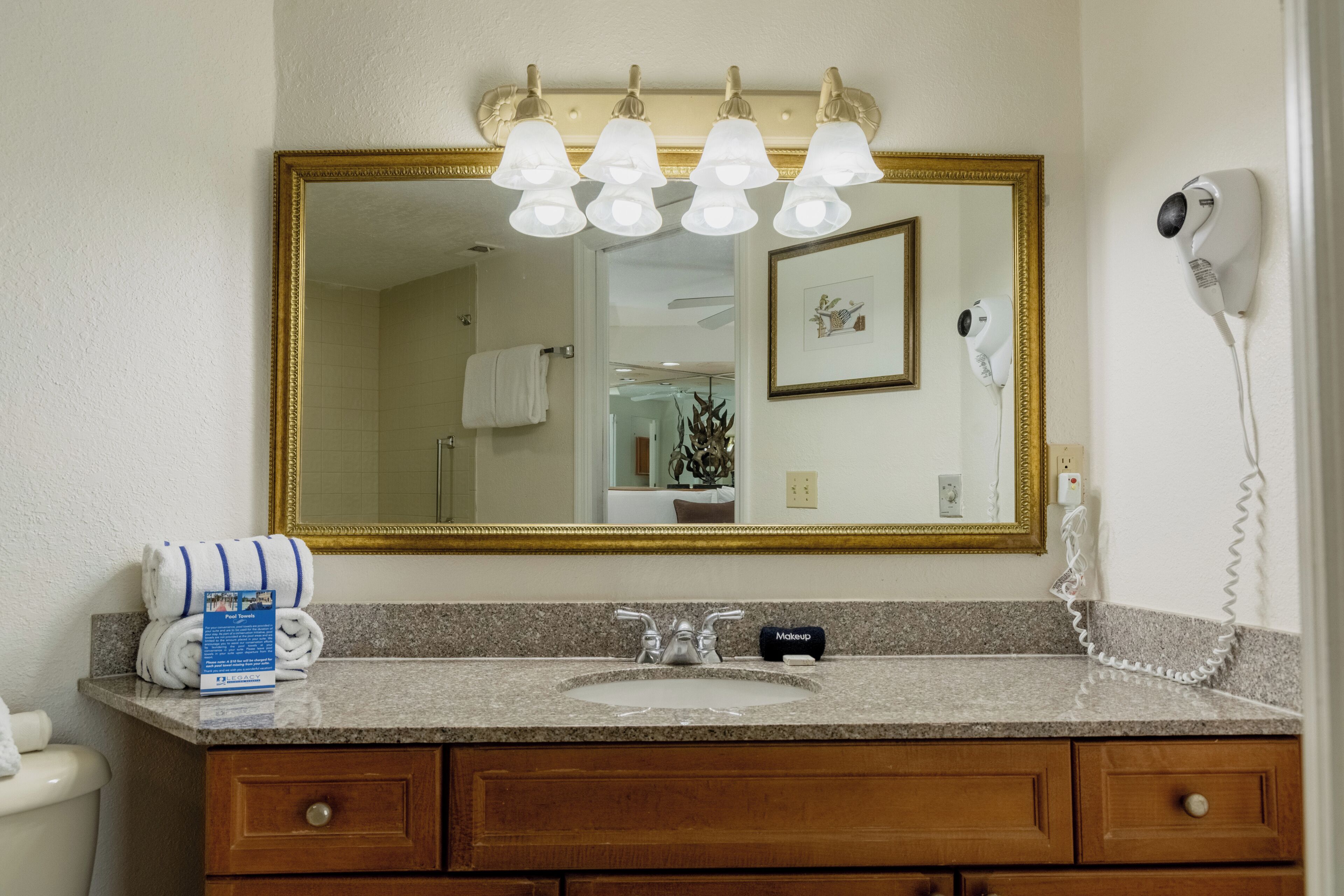 A bathroom with a sink, mirror, towel rack, and a hairdryer on the wall.