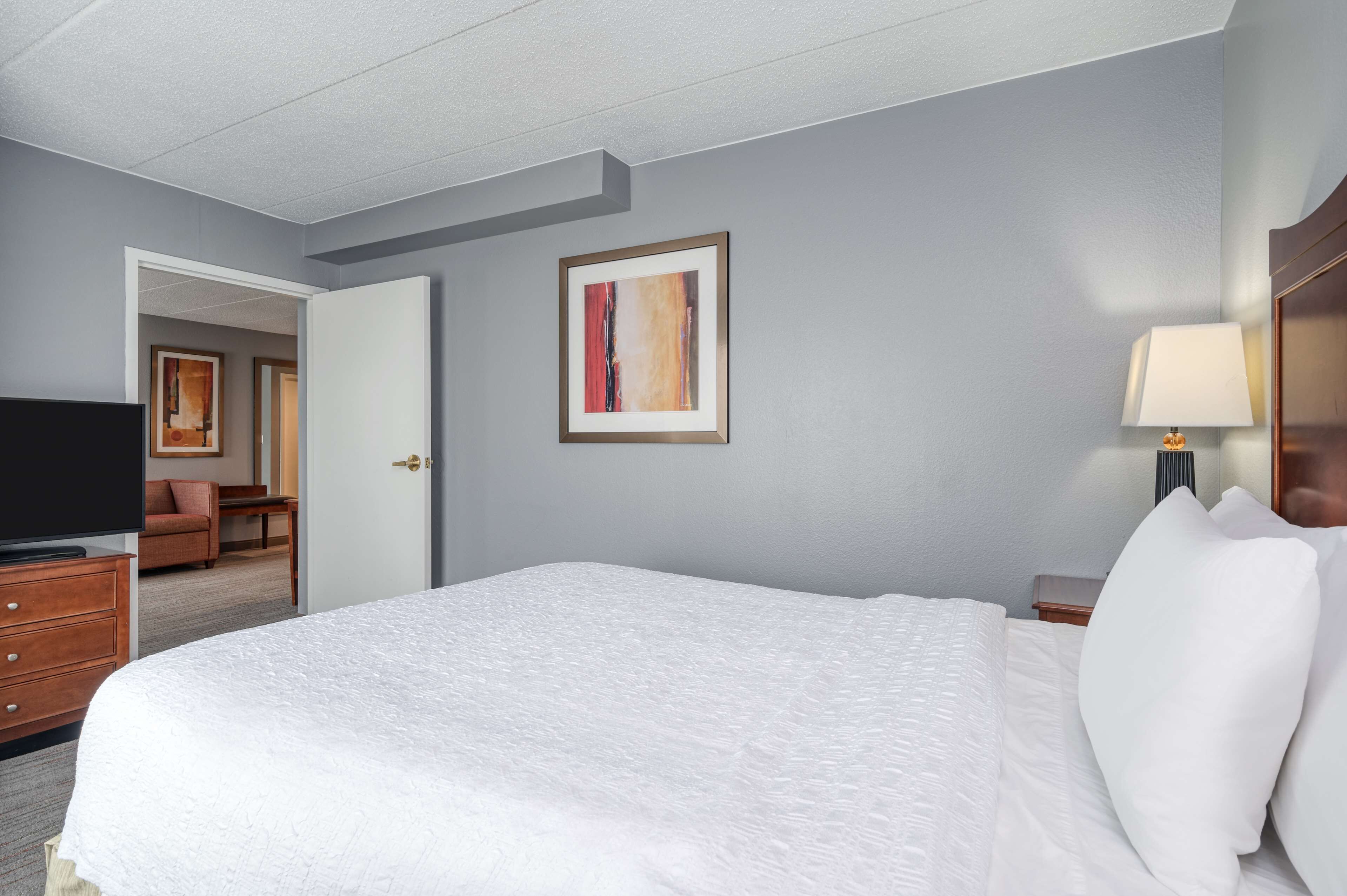 Una habitación de hotel con una cama grande, televisión, escritorio y una silla.