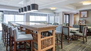 Un comedor de hotel con una larga mesa de madera, varias sillas y un mostrador de buffet.