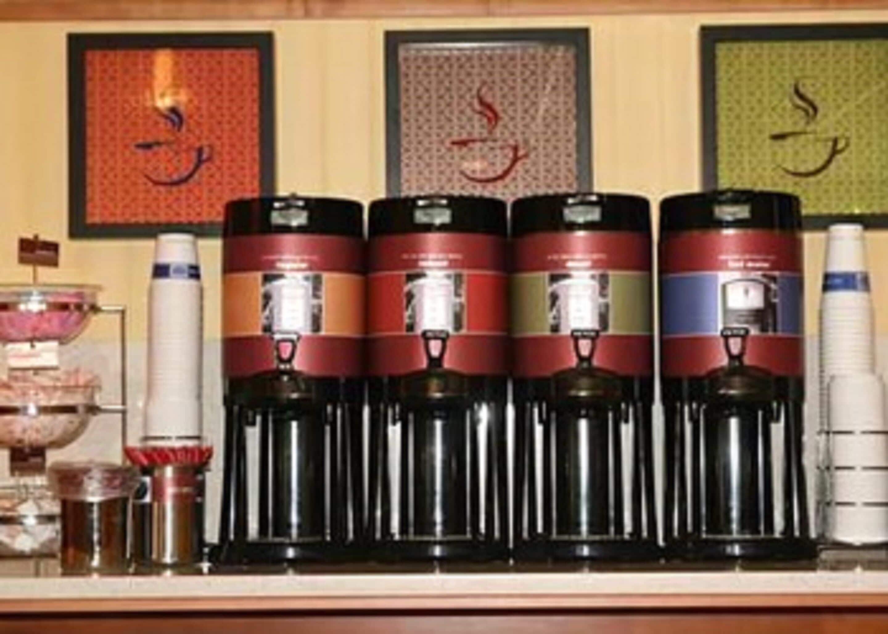 Una estación de café con varios dispensadores de café y un dispensador de agua.