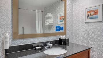 A bathroom with a large mirror, a sink, and a towel rack.