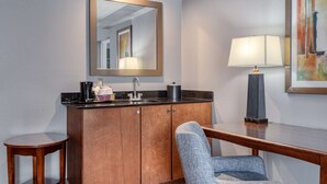Habitación de hotel con un armario de madera, un lavabo, un espejo, una silla y una mesa.