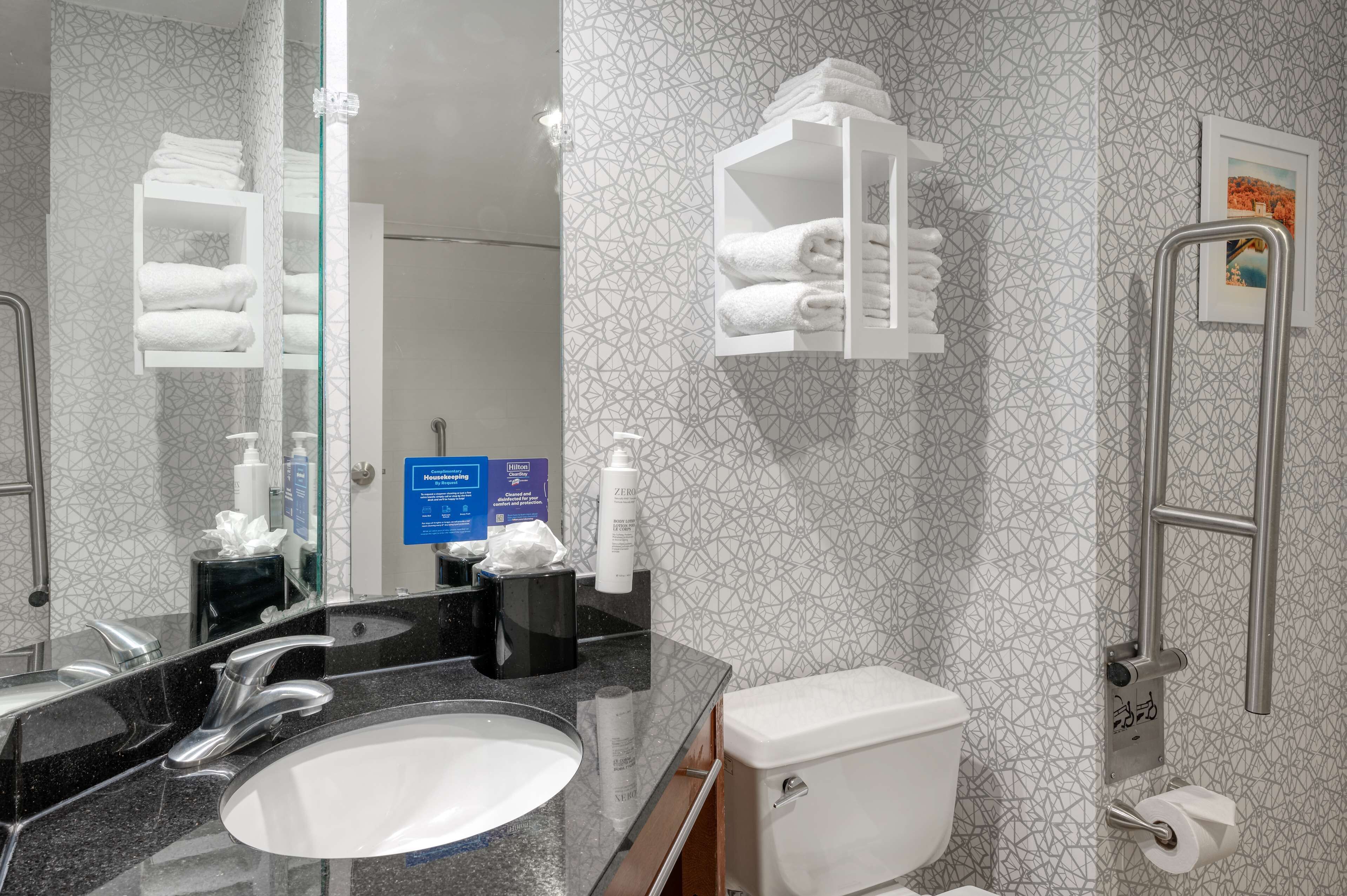 Ein modernes Badezimmer mit großem Spiegel, Waschbecken, Toilette und Duschbereich.