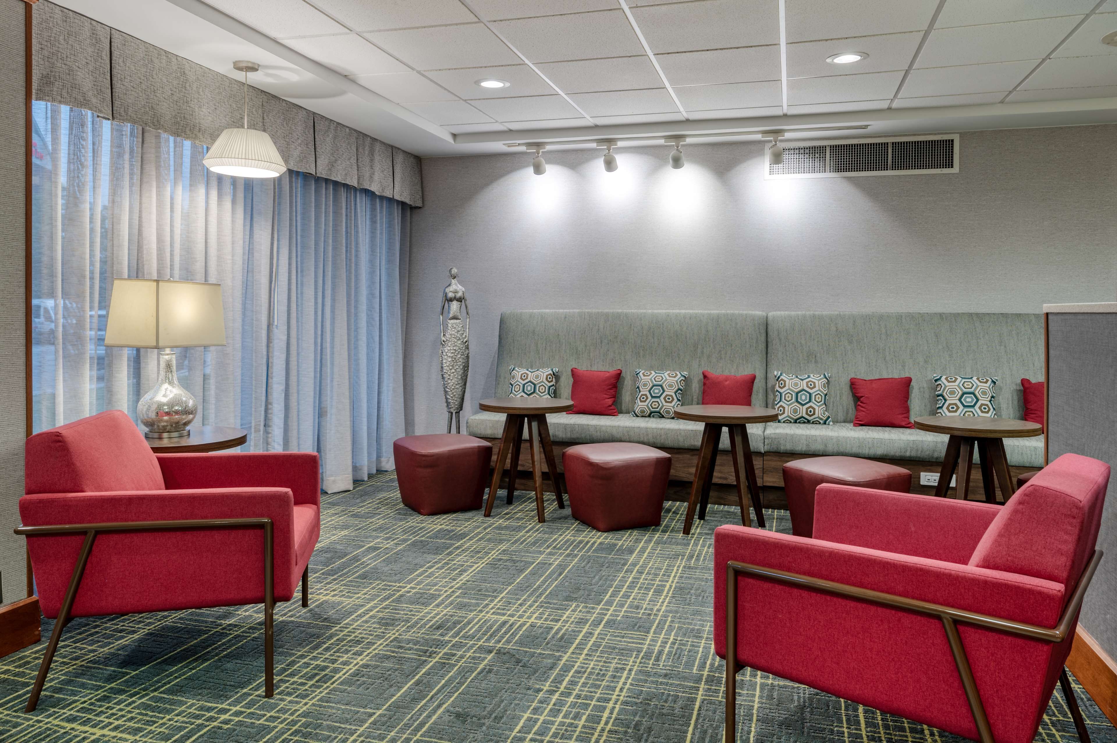 Una habitación de hotel con sofá, dos sillones, una mesa y una lámpara.